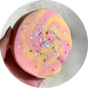 a pink and yellow swirled slime with gold star glitter on top and blue circular glitter 